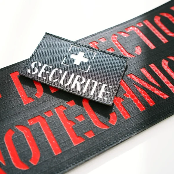 Bandeaux laser-cut noirs avec inscriptions Sécurité en rouge et blanc.