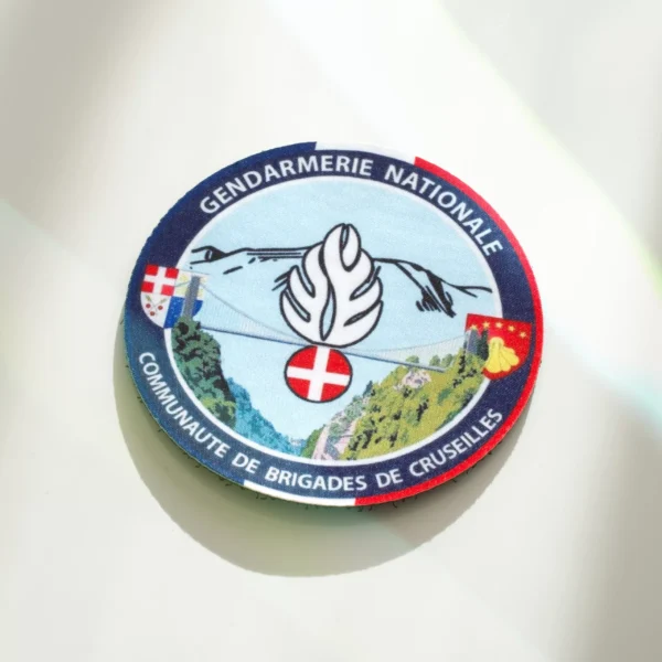 Écusson sublimé de la communauté de brigades de Cruseilles, avec montagnes et blason.